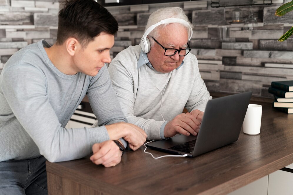 the younger is teaching the seniors to use a laptop